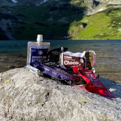 słodycze i żel energetyczny This-1 sfotografowane na tle górskiego jeziora