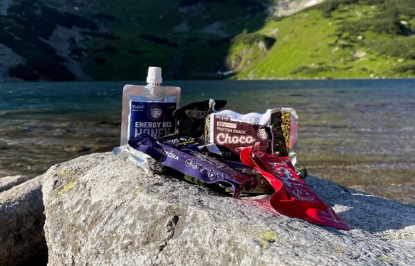 słodycze i żel energetyczny This-1 sfotografowane na tle górskiego jeziora
