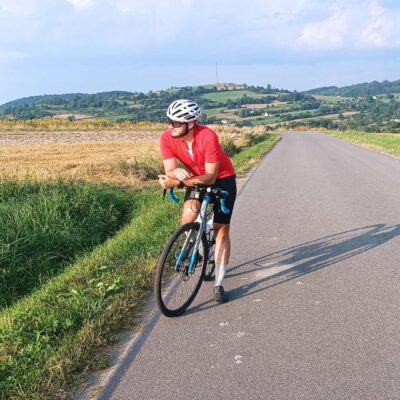 rowerzysta zatrzymał się na poboczu pustej, malowniczej drogi