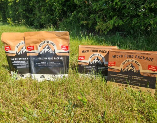 cztery racje żywnościowe Maverick Food Package ustawione na trawniku