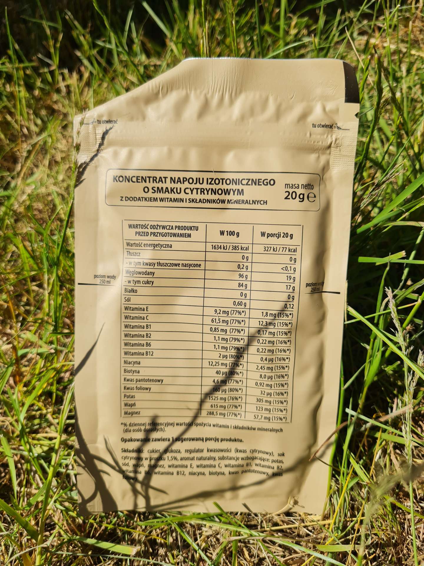 saszetka z proszkiem do przygotowania napoju izotonicznego, położna na trawniku