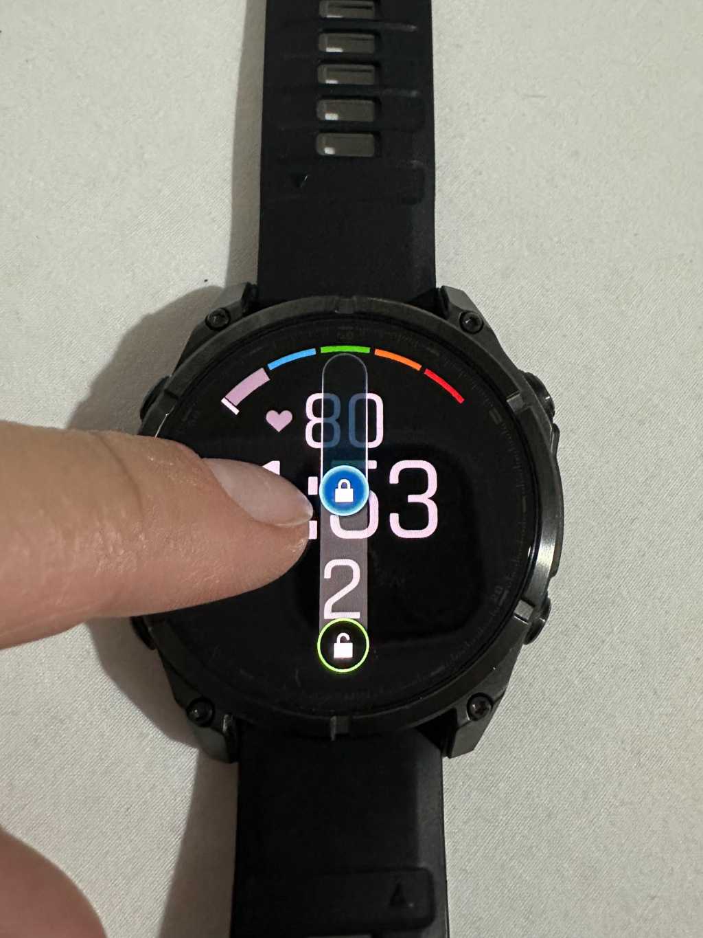 palec zbliżony do wyświetlacza garmina 8 fenix AMOLED, na ekranie opcja odblokowywania