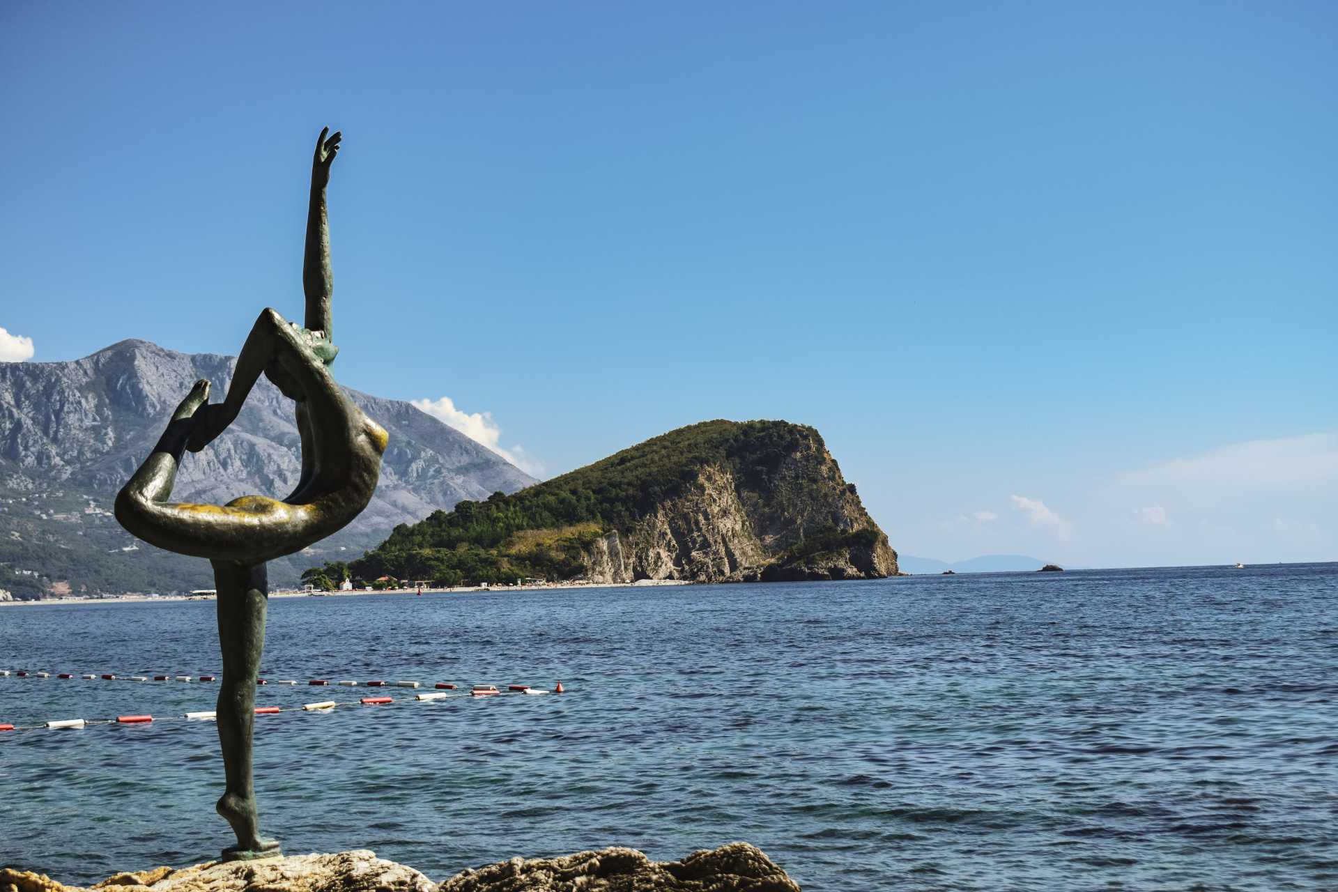 malownicze zdjęcie wykonane z plaży, widać skalną wyspę pośród błękitnego morza