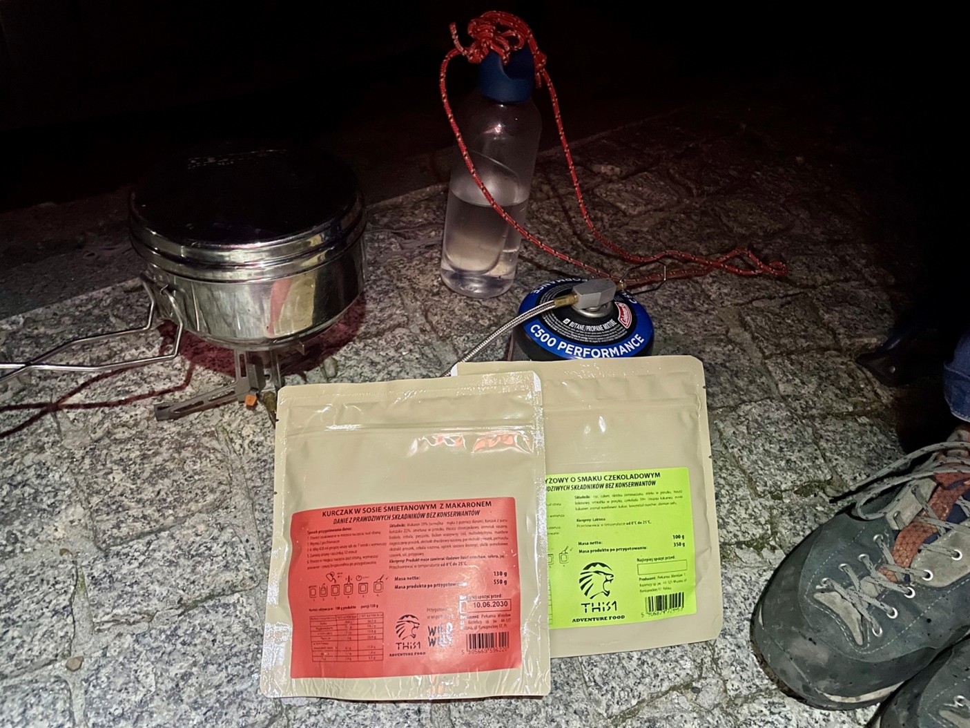 dwa dania liofilizowane This-1 położone na skałach, obok profesjonalny ekwipunek górski