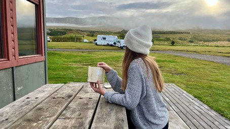 kobieta w czapce siedzi przy drewnianym stole, w rękach trzyma danie liofilizowane. Testy żywności liofilizowanej This-1 przeprowadzliśmy także na Islandii