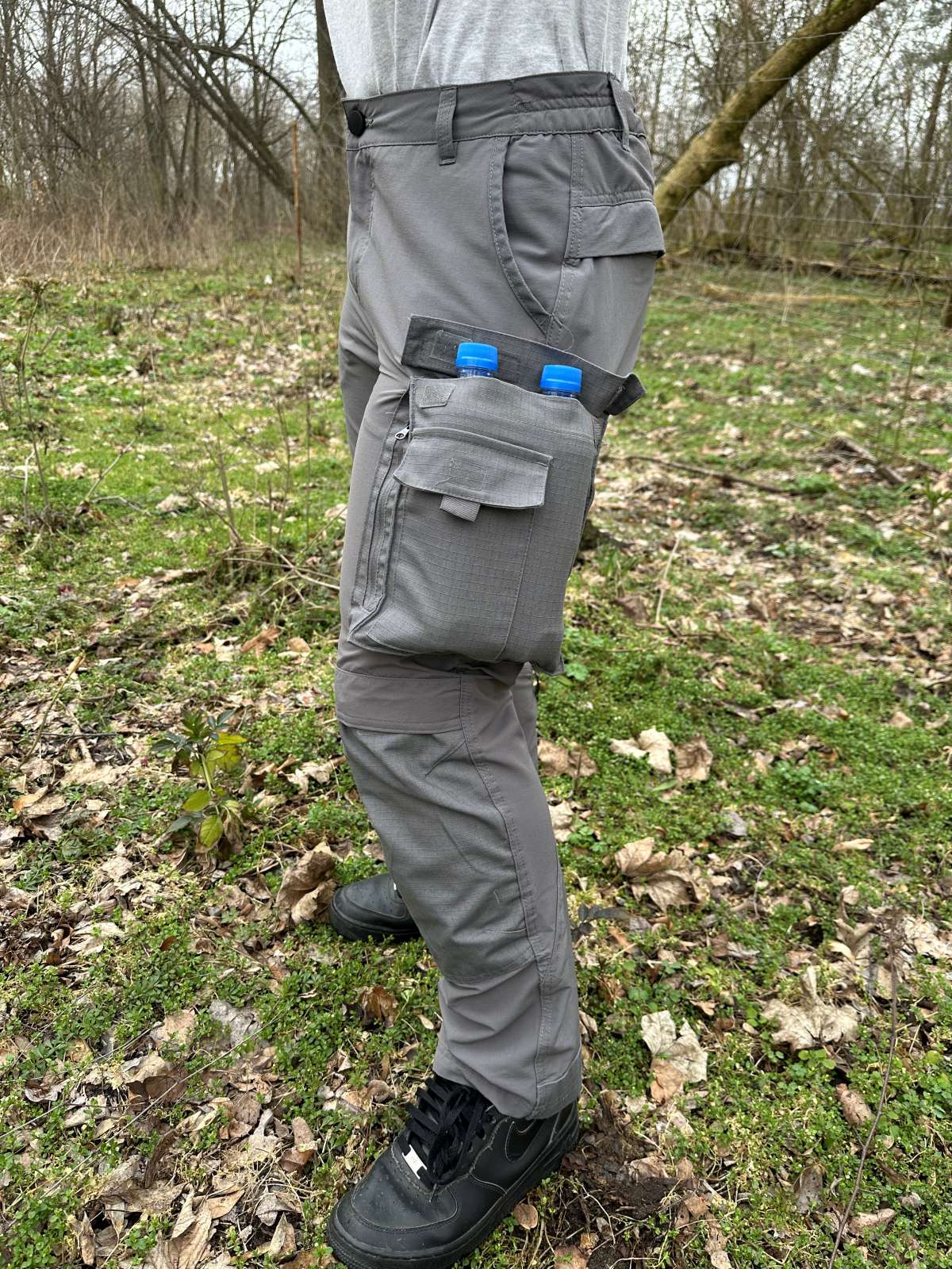 zbliżenie na umieszczoną z boku nogawki kieszeń spodni, w środku dwie półlitrowe butelki wody